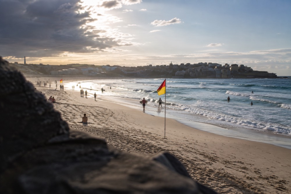 Red and yellow patrol flags spaced along the sand at Bondi Beach