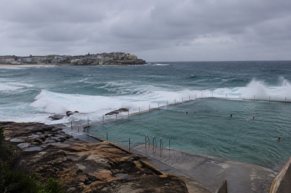Ocean pool on a sandstone headland with waves breaking against its far wall