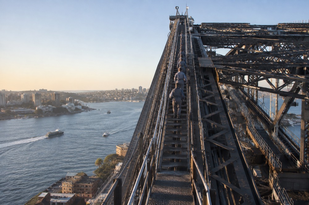Steel ladders inside the bridge structure, lit by overhead lamps, leading up toward the arch