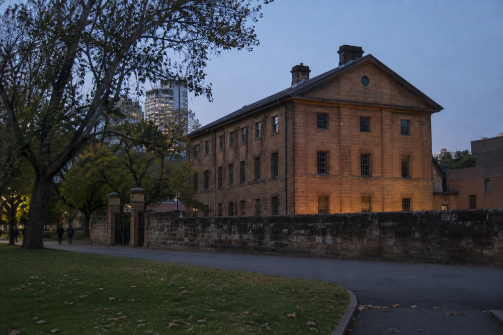 A three-storey Georgian sandstone building with a row of small windows beside a leafy city park