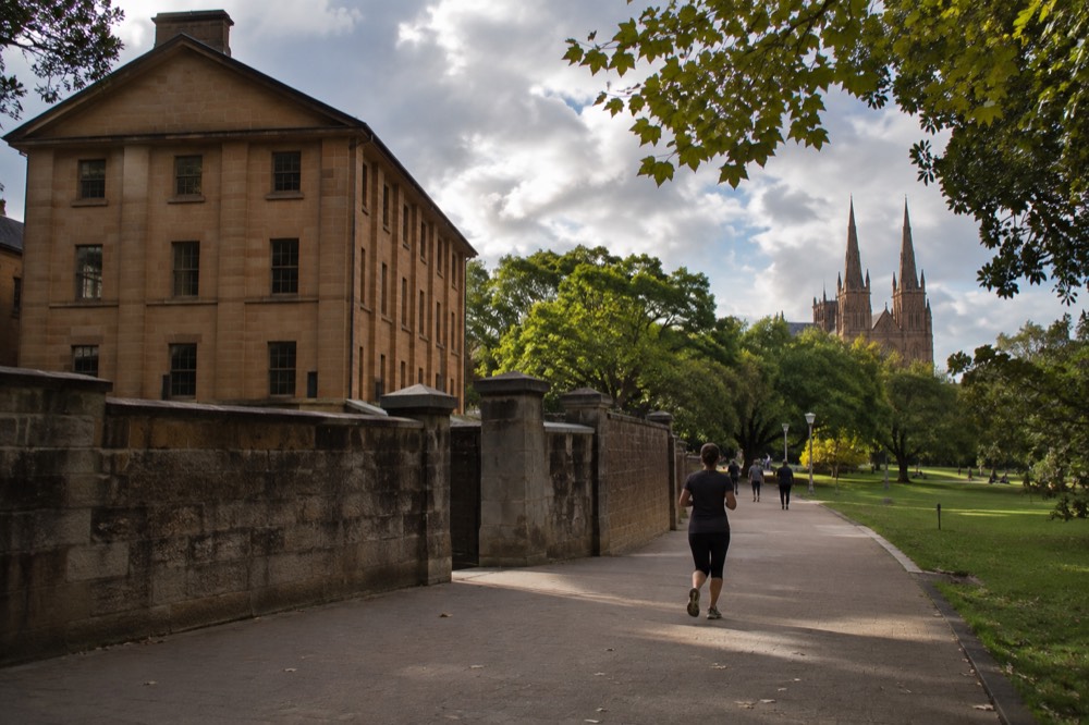 A tall cathedral with twin spires seen across a green park lawn
