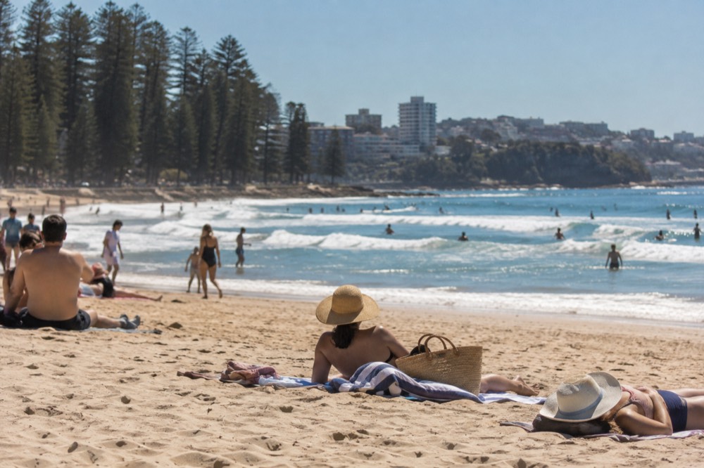 Sun hats and towels on sand next to a beach bag