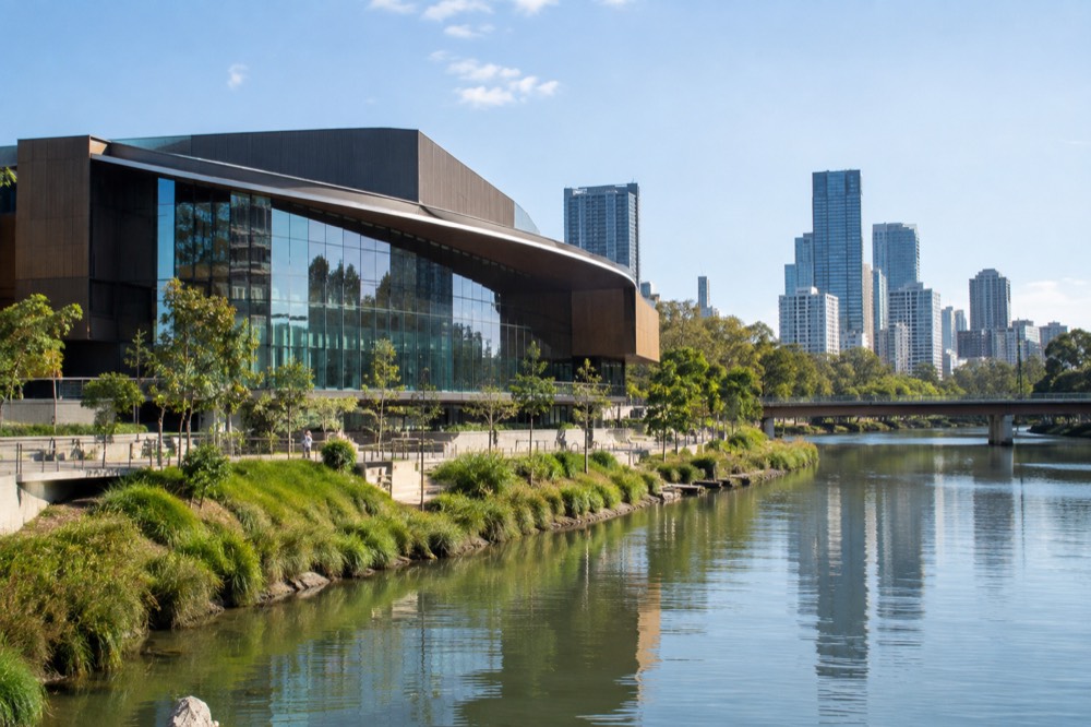 A new modern museum building beside a river in Parramatta with the city skyline behind it