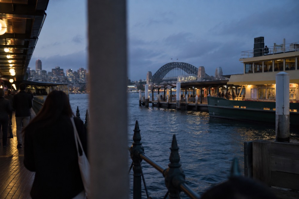 A busy harbourside precinct with waterfront walkways and ferry terminals at dusk