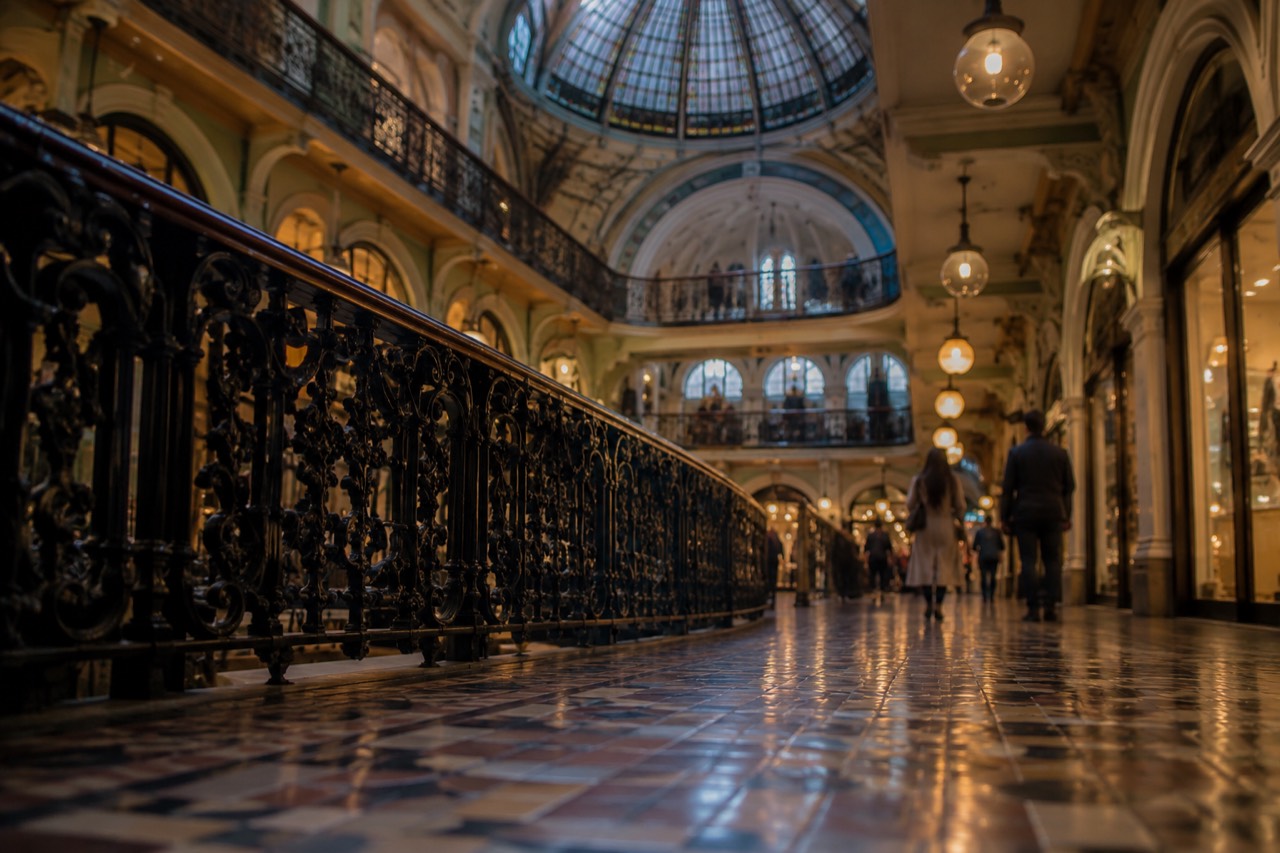 Ornate heritage shopping arcade interior with a high glass dome and balustraded upper galleries