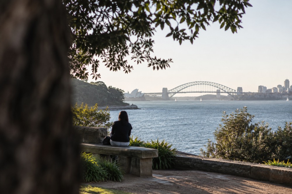 Carved sandstone bench on a point overlooking a harbour with a bridge in the distance