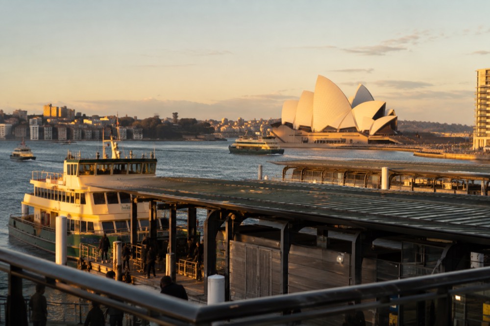 Ferries and trains at Circular Quay with the Opera House beyond the wharves