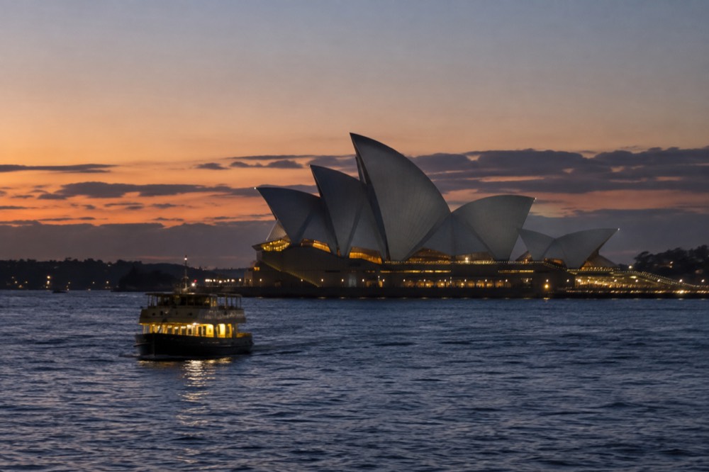 The Opera House at dusk with interior lights glowing through the foyer glass