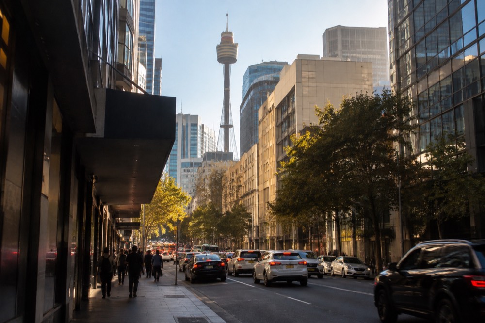 Busy city street with a tall golden tower visible above retail buildings