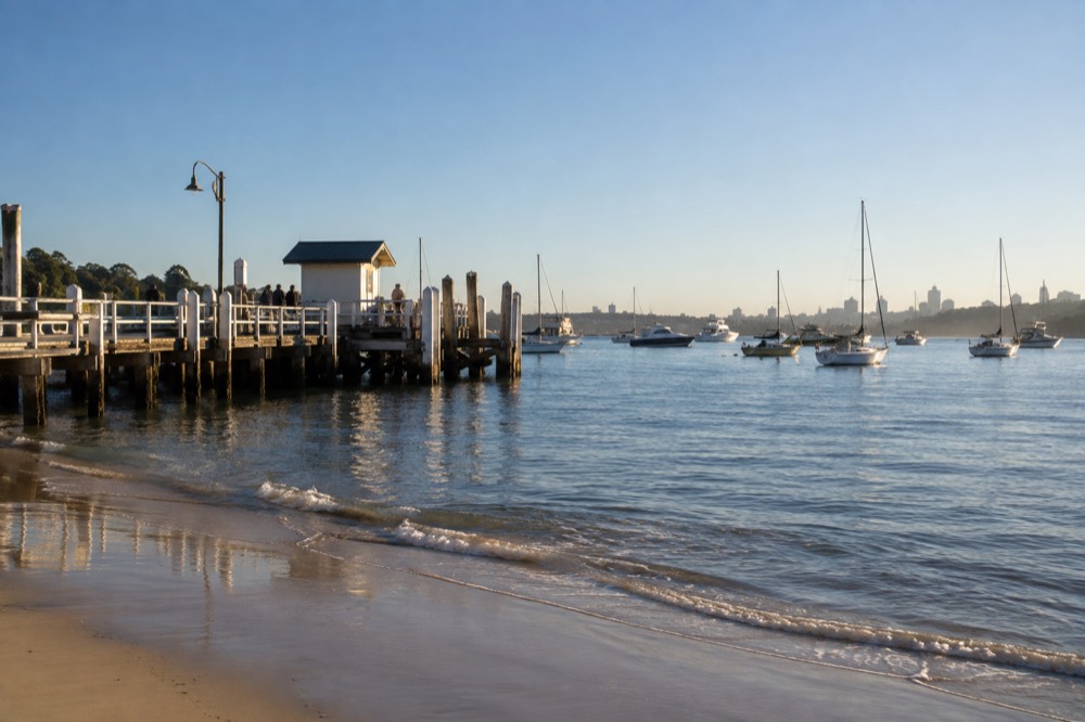 Ferry wharf at a harbourside village with calm blue water and moored boats