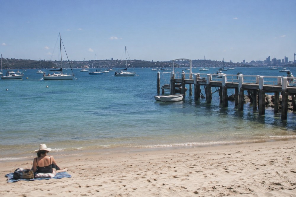 Sandy cove with calm turquoise water and a timber jetty extending into the bay