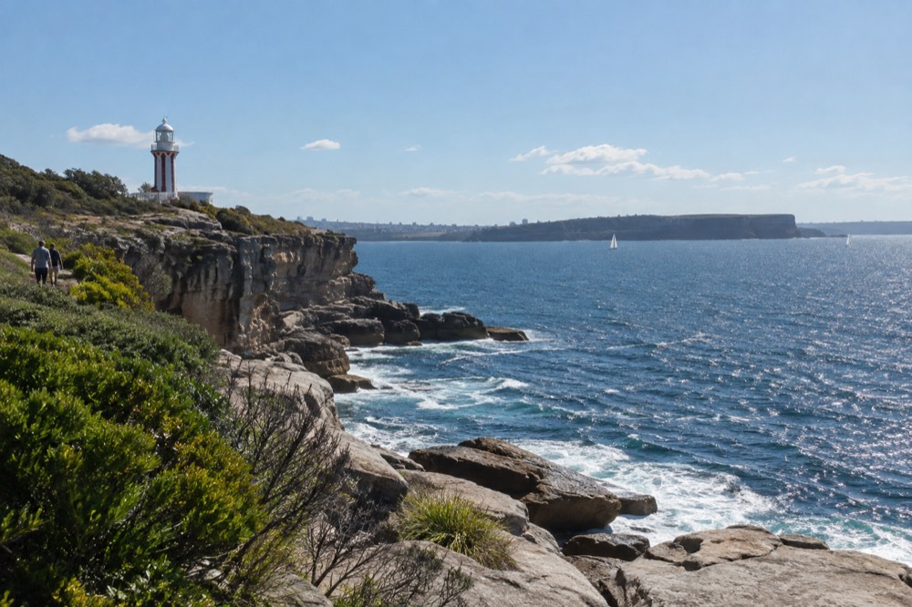 Ocean cliff edge with a lighthouse on the headland and open sea beyond