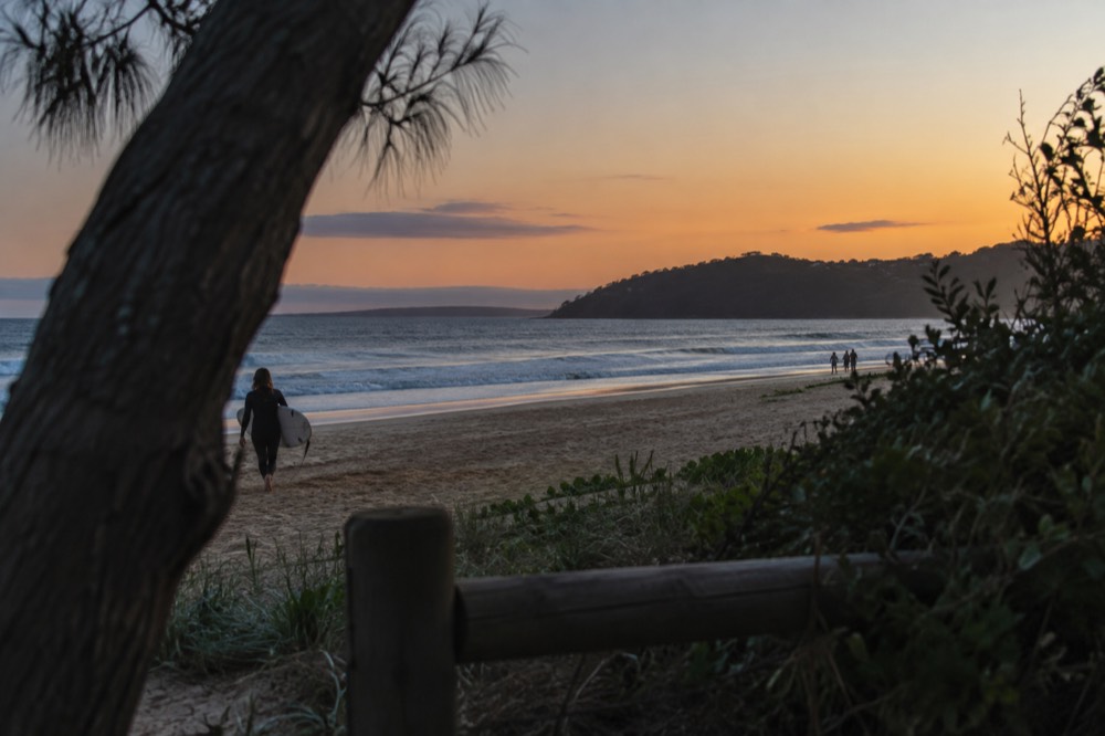 A quiet surf beach in late afternoon light with long shadows on the sand