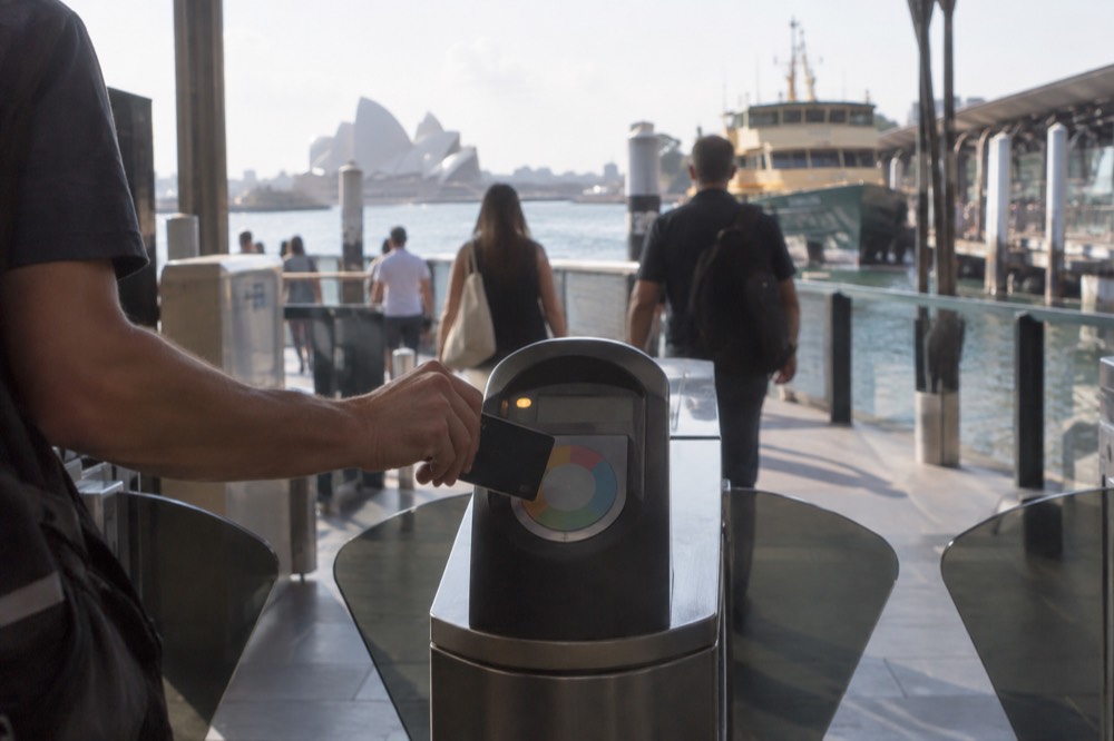 A contactless credit card being tapped on an Opal reader at a station gate