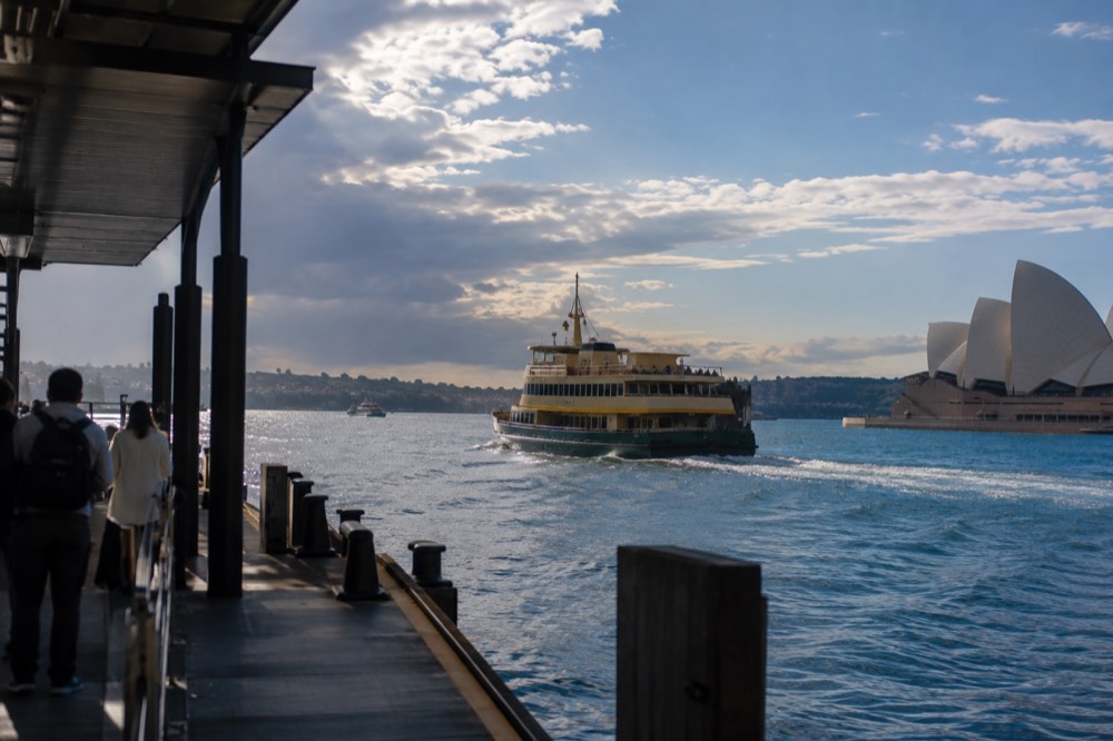 A ferry crossing blue harbour water toward a headland