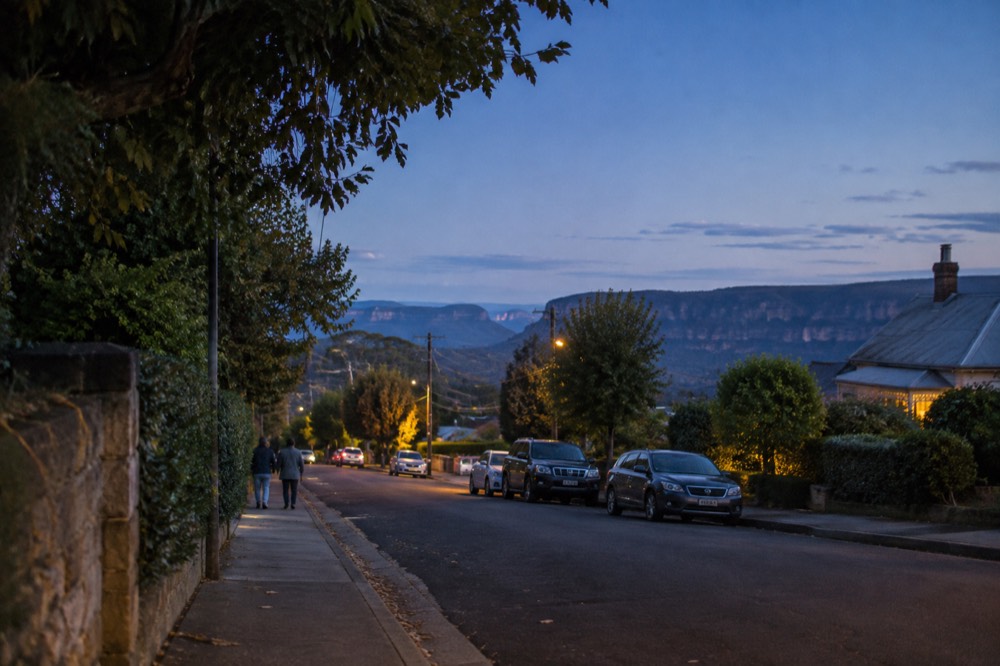 A mountain town street with autumn trees under a clear blue sky