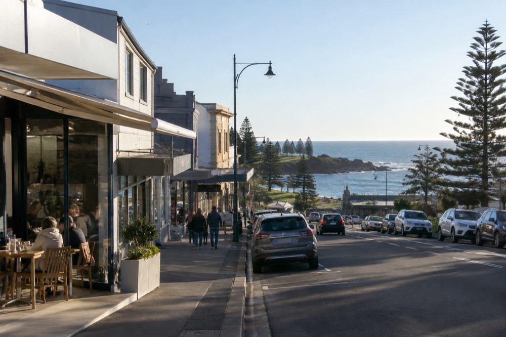 A small coastal town main street with cafes and shopfronts on a sunny morning