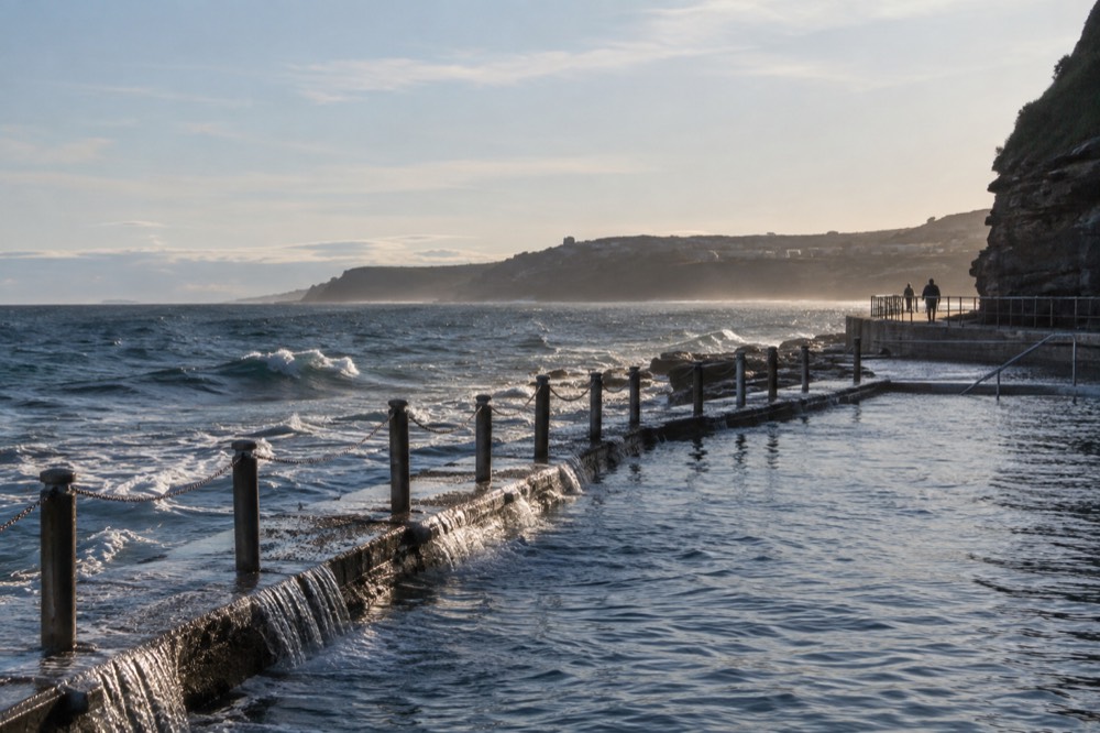 Ocean pool at the base of a headland with gentle waves spilling over the edge