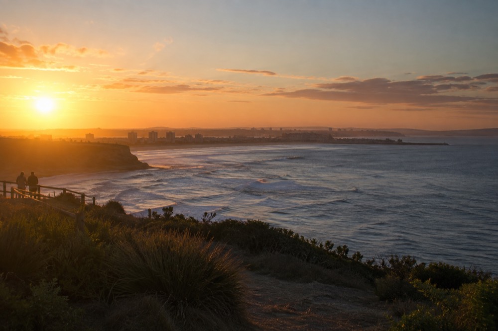 Sunset over a coastal headland with the city skyline in the distance