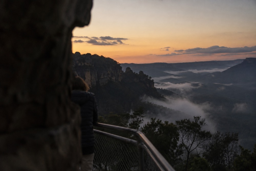 Steep forested valley walls rising above a misty valley floor at Katoomba