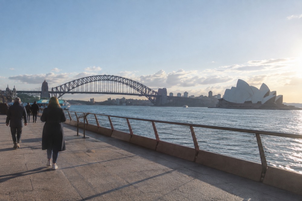 Level paved promenade outside the Sydney Opera House with the harbour bridge behind it