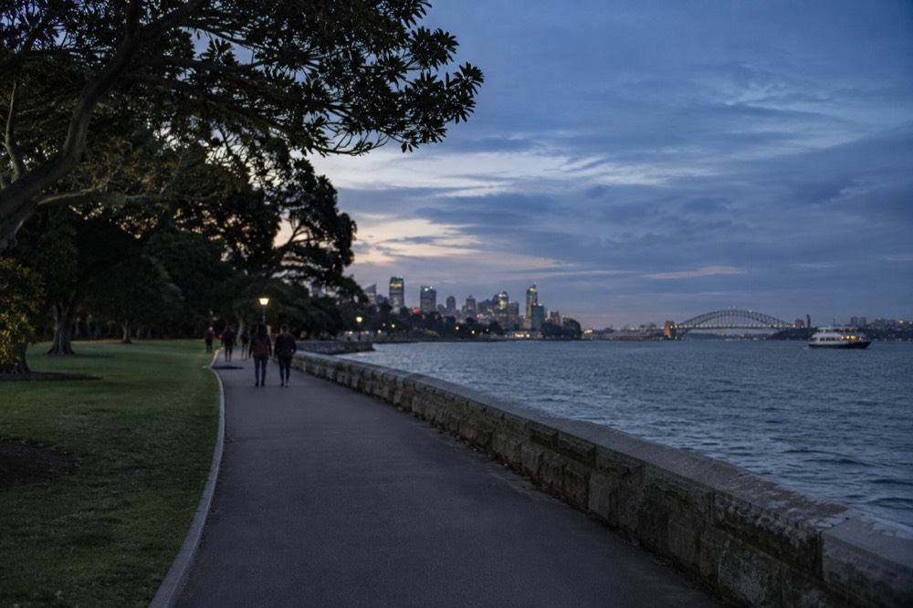 A long level waterfront path through the Royal Botanic Garden with harbour water alongside