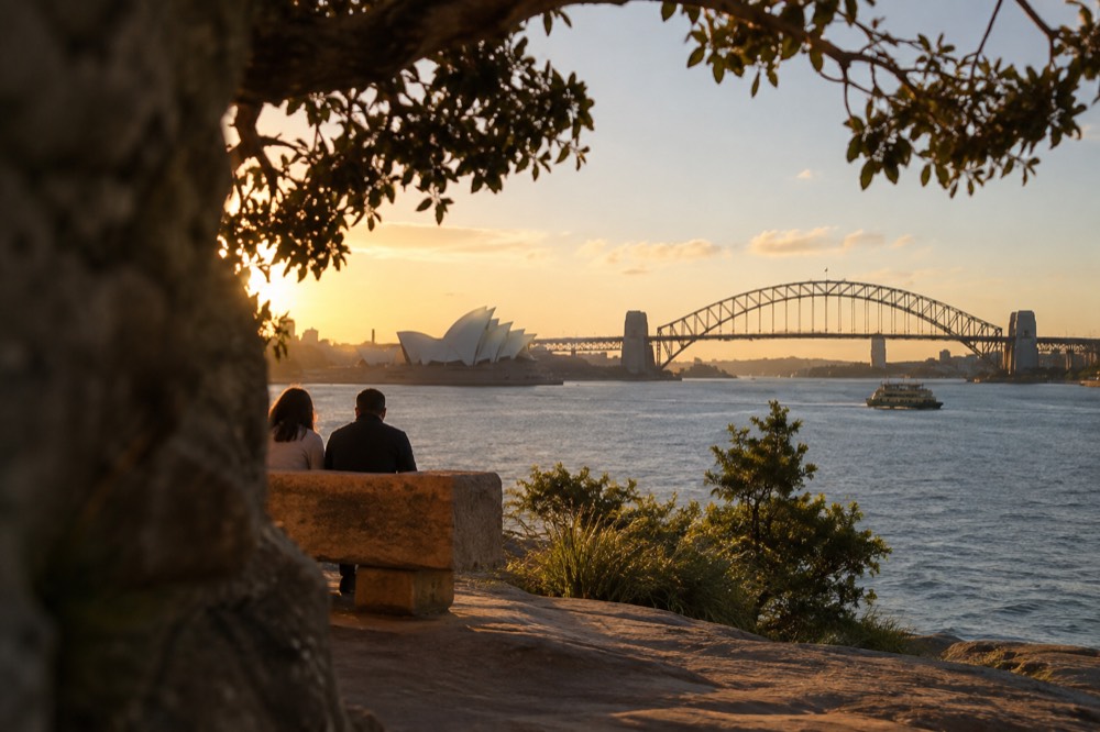 A sandstone bench on a harbour point overlooking the Opera House and Harbour Bridge across a cove