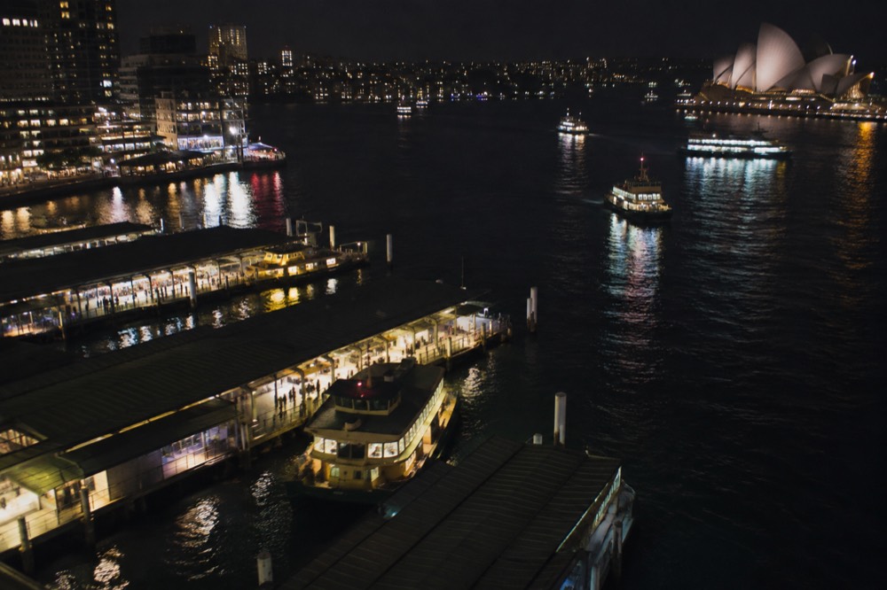 City lights reflected in harbour water at night seen from high above the bridge