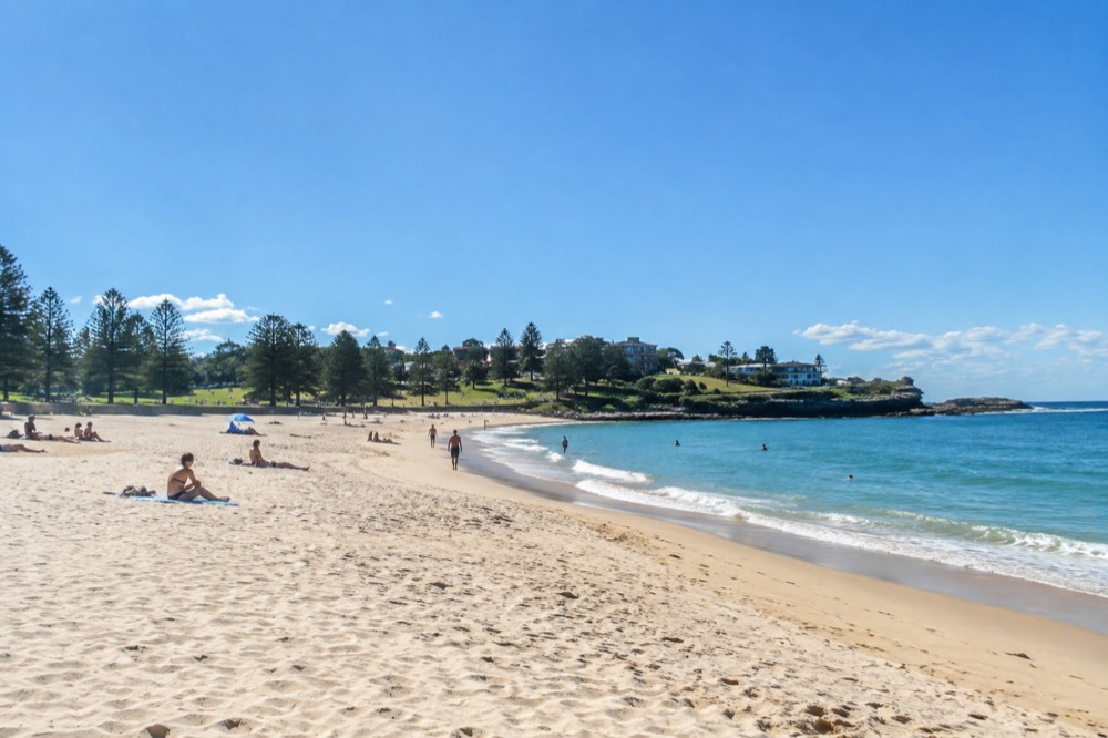 Coogee Beach at the end of the walk, wide sand with lawns and fig trees behind