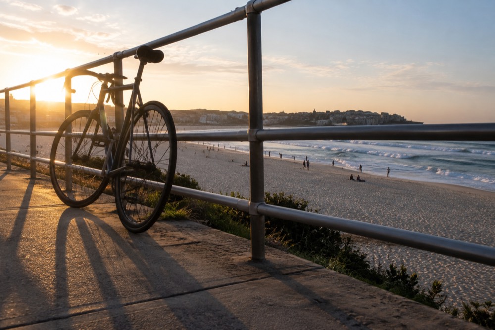 A bicycle leaning against a railing above Bondi Beach