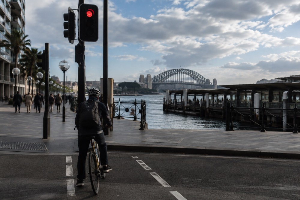A cyclist wearing a helmet waiting at a signalised crossing in Sydney