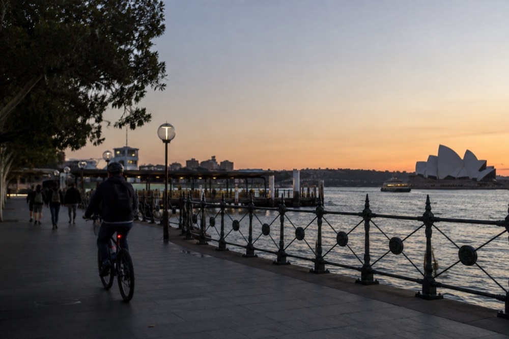 A cyclist riding along the harbour foreshore under a clear winter sky