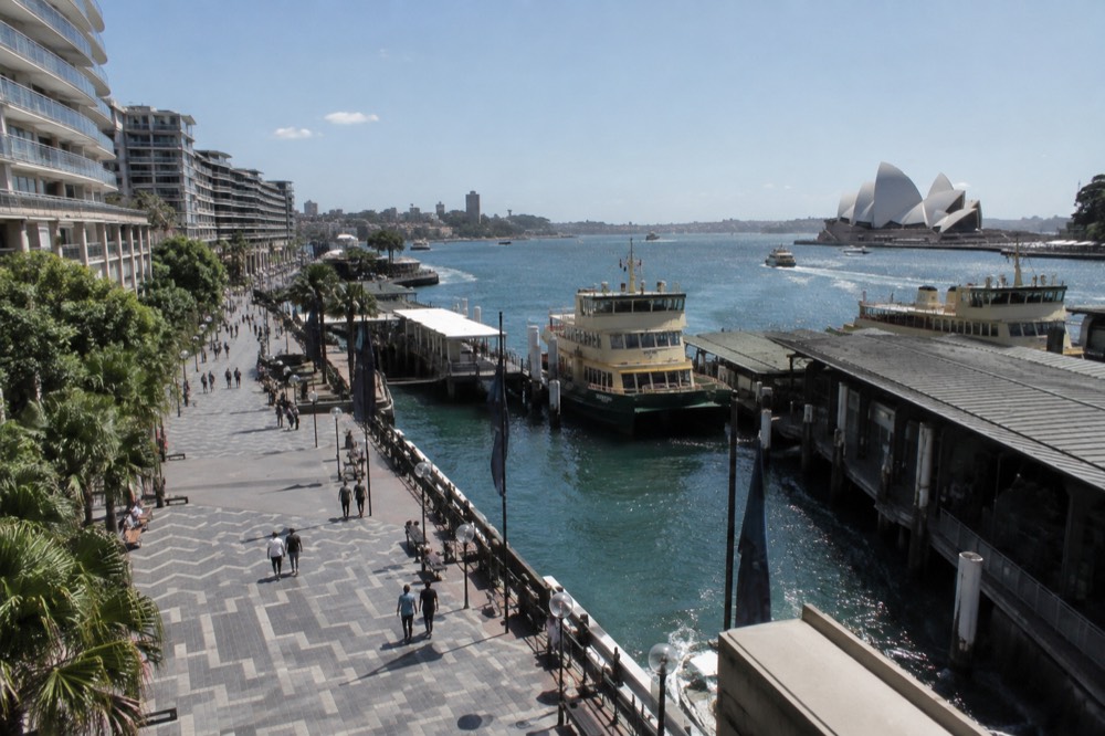 A pedestrian street in central Sydney with the harbour beyond