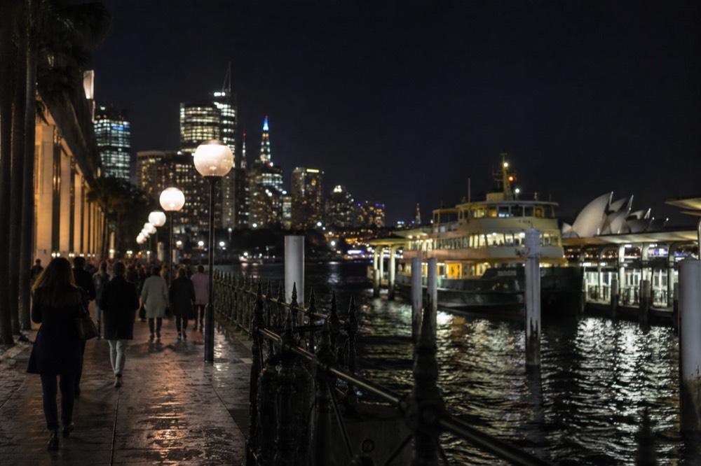 A busy inner-city Sydney street in the evening with neon signs and lit shopfronts