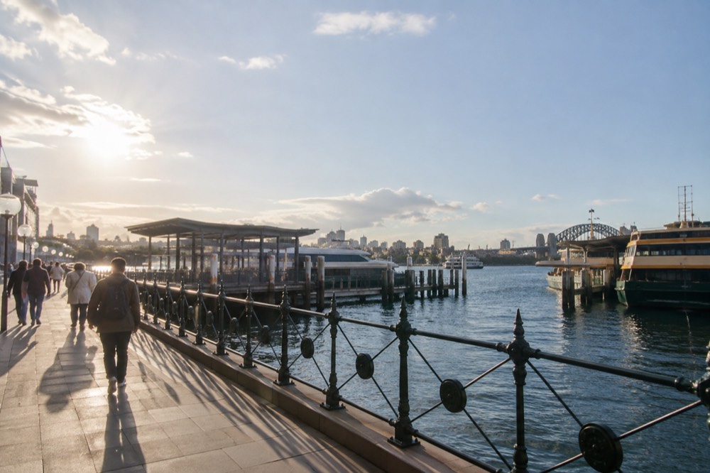 A wide Sydney harbour promenade in daylight with ferry terminals and moored boats