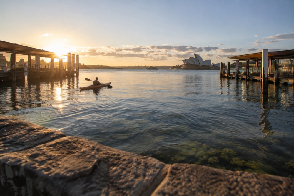 A single kayak floating on glassy water above seagrass in a sheltered cove