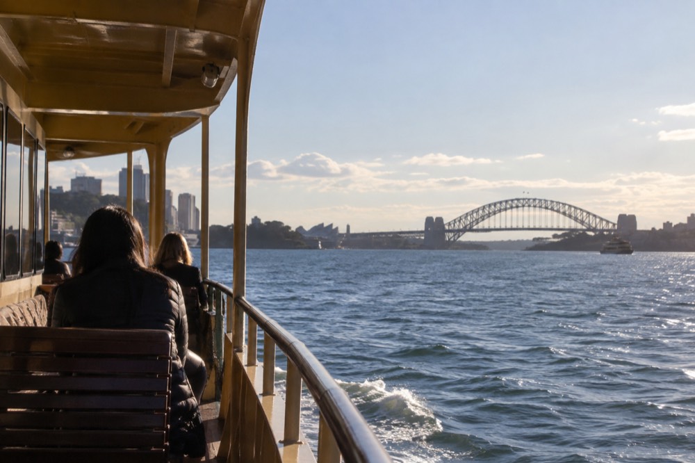 A ferry deck in late afternoon light with the harbour bridge on the horizon
