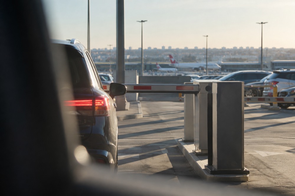 Car park entry boom gate with digital sign above a queue of cars