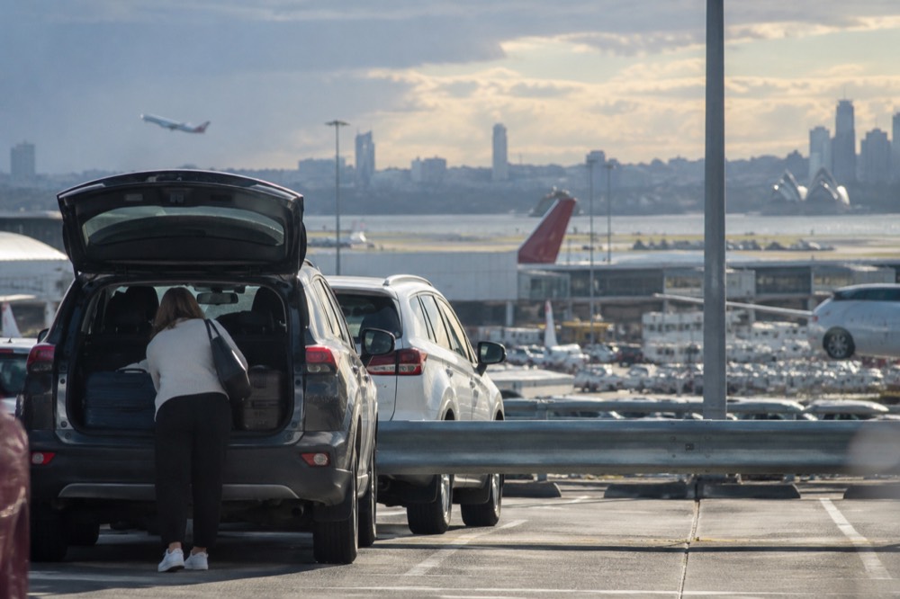 Traveller loading luggage into a car boot in an airport car park