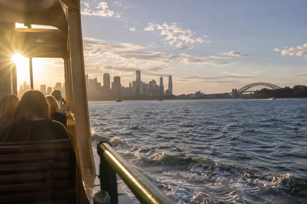 Ferry crossing open harbour water with city skyline and zoo shoreline ahead