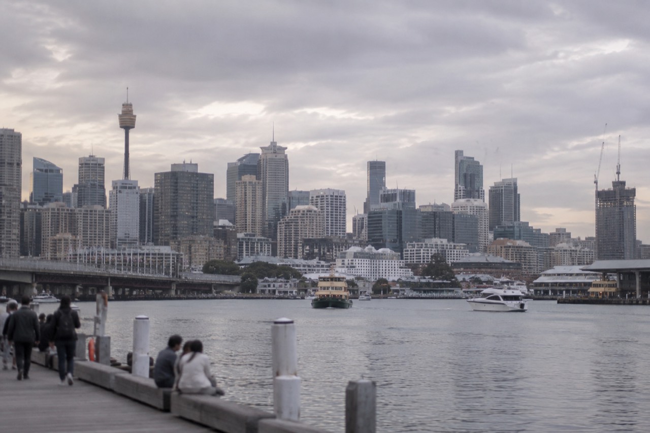 Sydney city skyline seen across Darling Harbour water at late afternoon