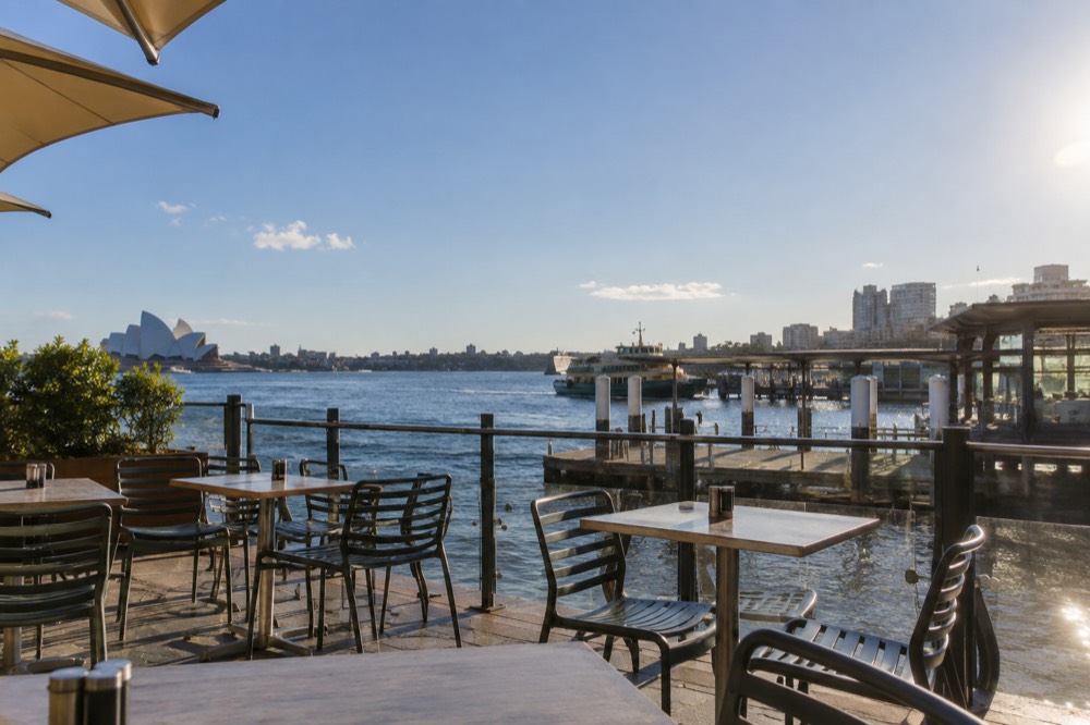 A café terrace with empty tables under a clear blue winter sky in Sydney