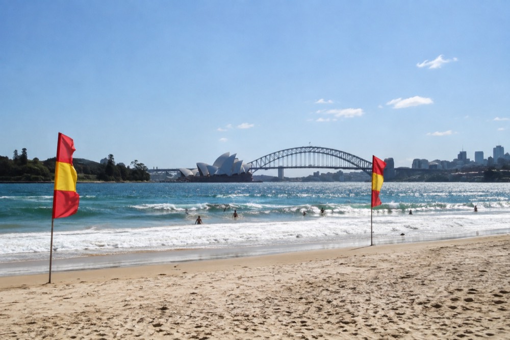 Red and yellow patrol flags on a sandy beach in front of rolling surf