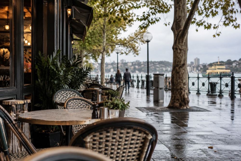 A café frontage with outdoor tables on a tree-lined Sydney street