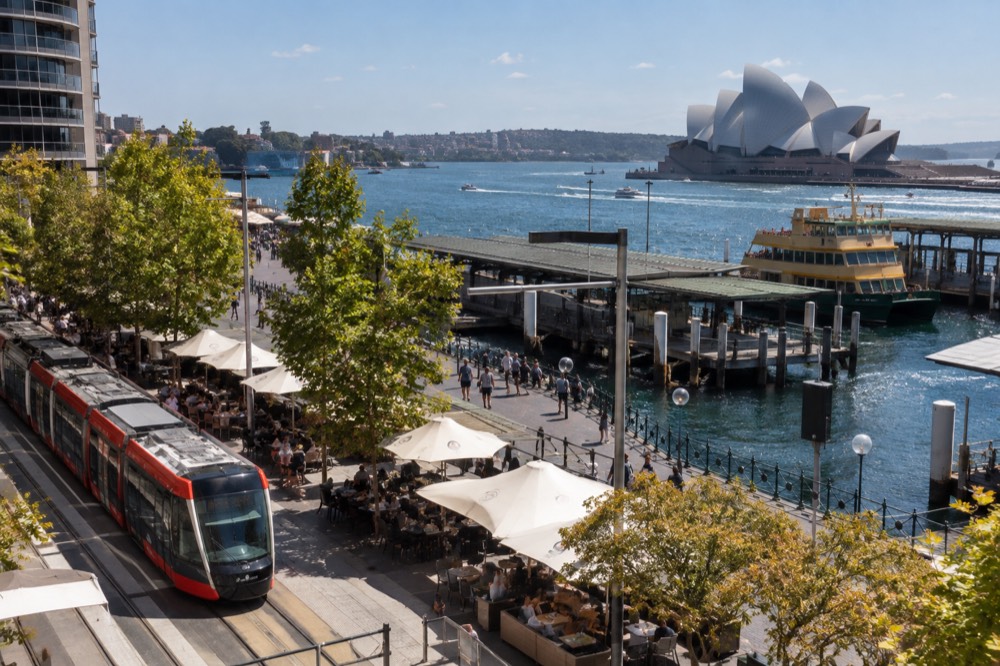 A light rail tram passing a café-lined street in inner Sydney