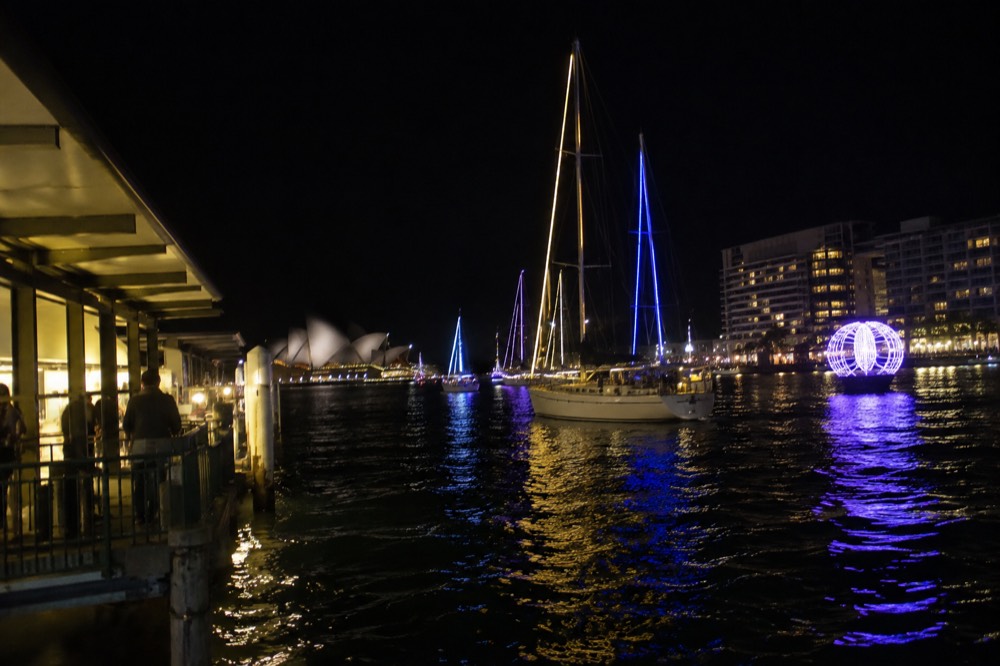 Illuminated sailing boats and light installations reflected in Sydney Harbour at night