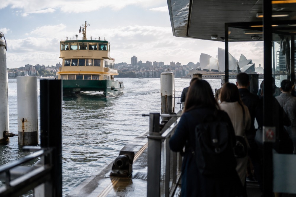 A Sydney ferry approaching a Circular Quay wharf with passengers waiting at the gate