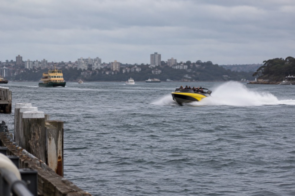 A jet boat throwing a spray of water across Sydney Harbour