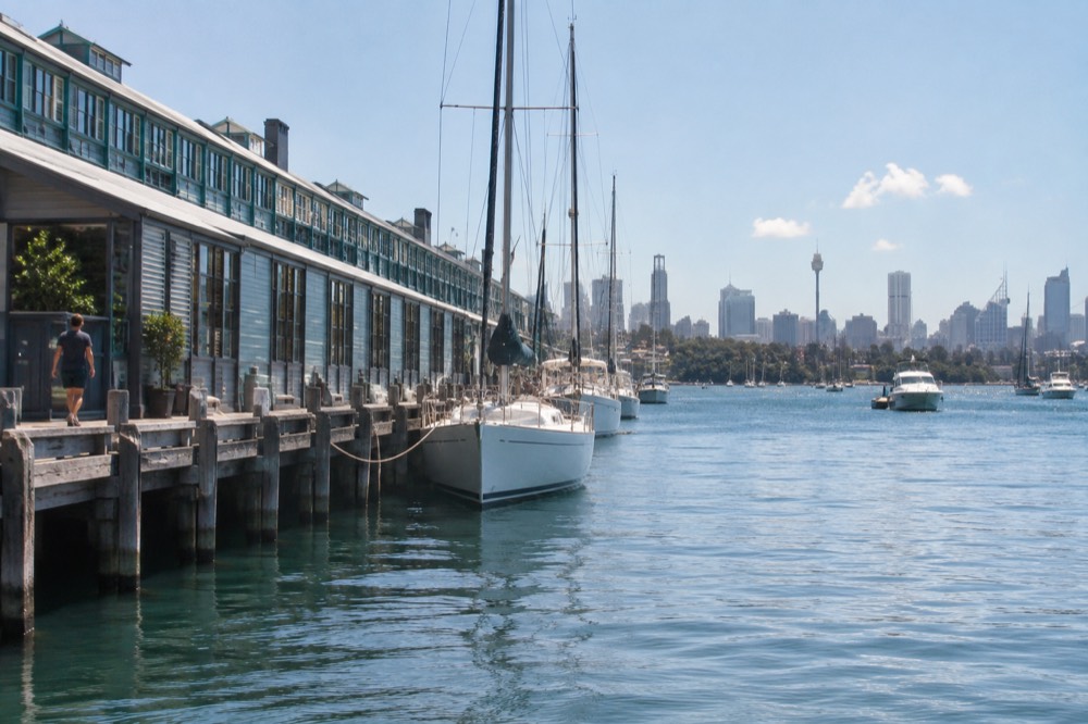 Timber finger wharf with heritage buildings moored against a city skyline