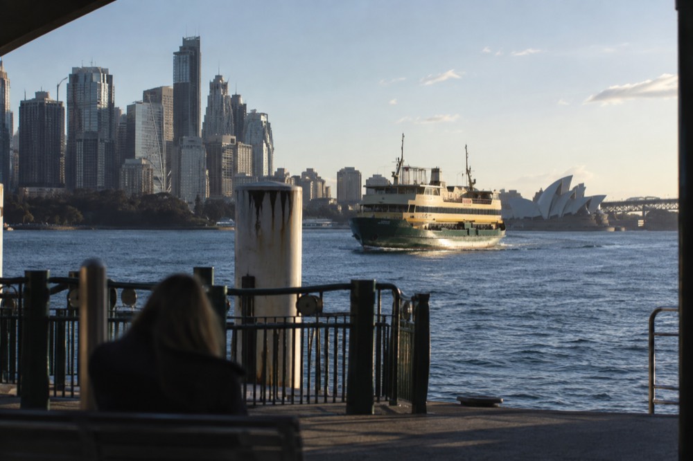 Green and cream ferry crossing the harbour with the city skyline behind